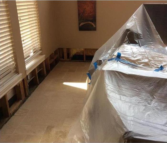Plastic sheet covering furniture, flood cuts performed on drywall due to flood damage.