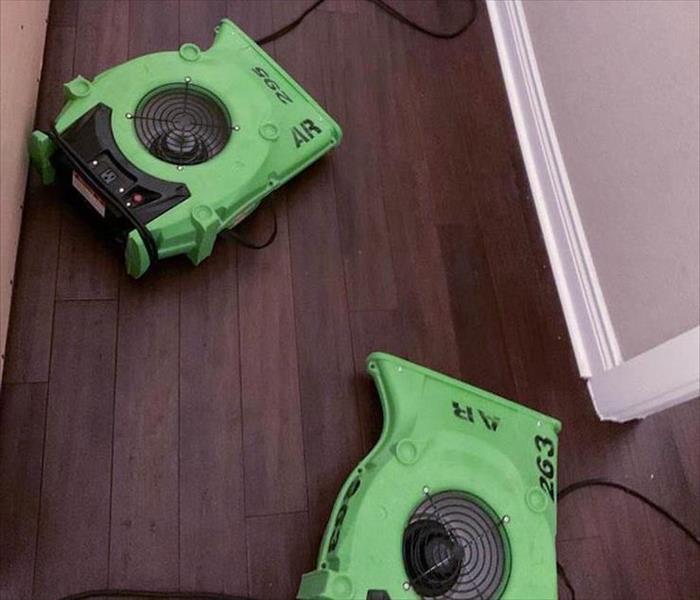 Two air movers on a kitchen floor.